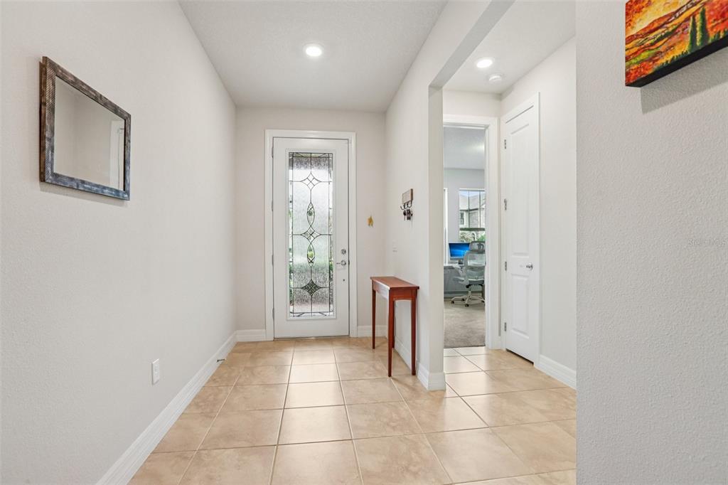 A bright entryway features beige tile flooring, a glass-paneled front door, and a small console table — 19246 BRIARBROOK DRIVE, TAMPA, FL