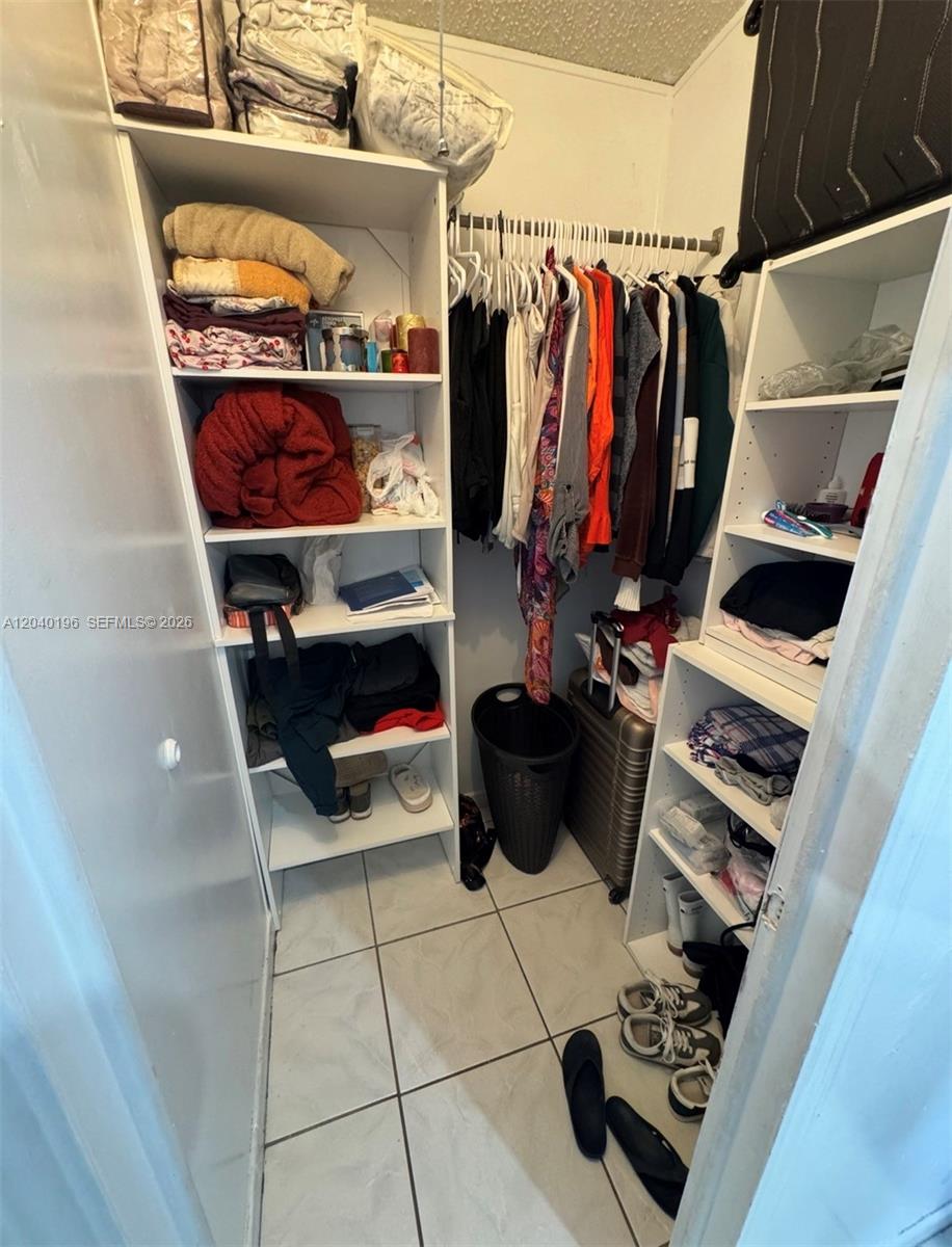 A walk-in closet features white shelving units on both sides and a central hanging rod — 1013 SW 128TH Ave, Miami FL 33184, MIAMI, FL
