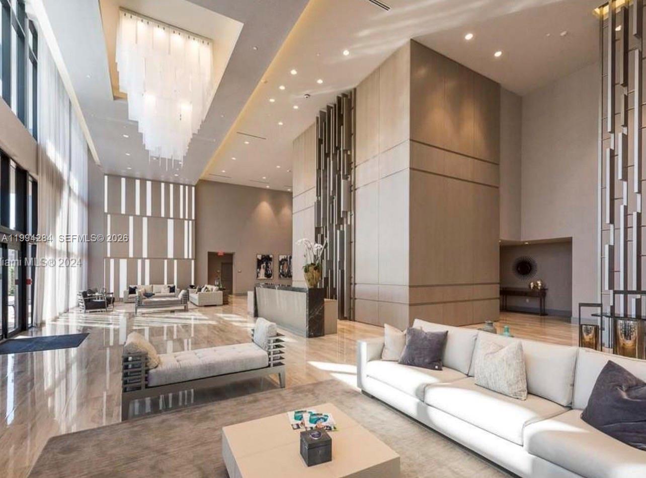 A spacious, modern lobby features high ceilings, a large crystal chandelier, and marble flooring — 5300 NW 85 # 1106, Doral FL 33166, DORAL, FL