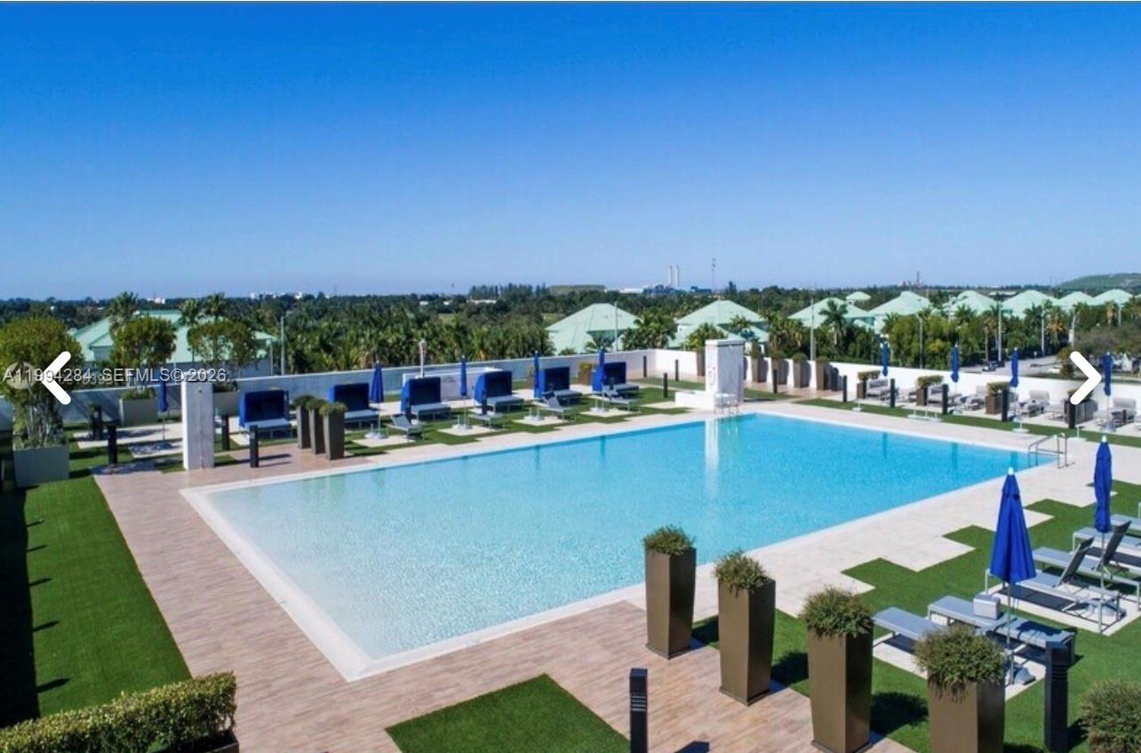 An outdoor swimming pool surrounded by lounge chairs and umbrellas on a paved deck — 5300 NW 85 # 1106, Doral FL 33166, DORAL, FL