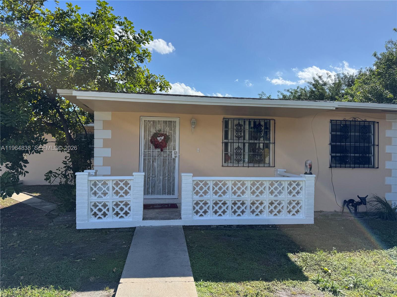 A single-story house features a peach-colored exterior, a white decorative block porch, and security bars — 36 NW 151st St, Miami FL 33169, MIAMI, FL