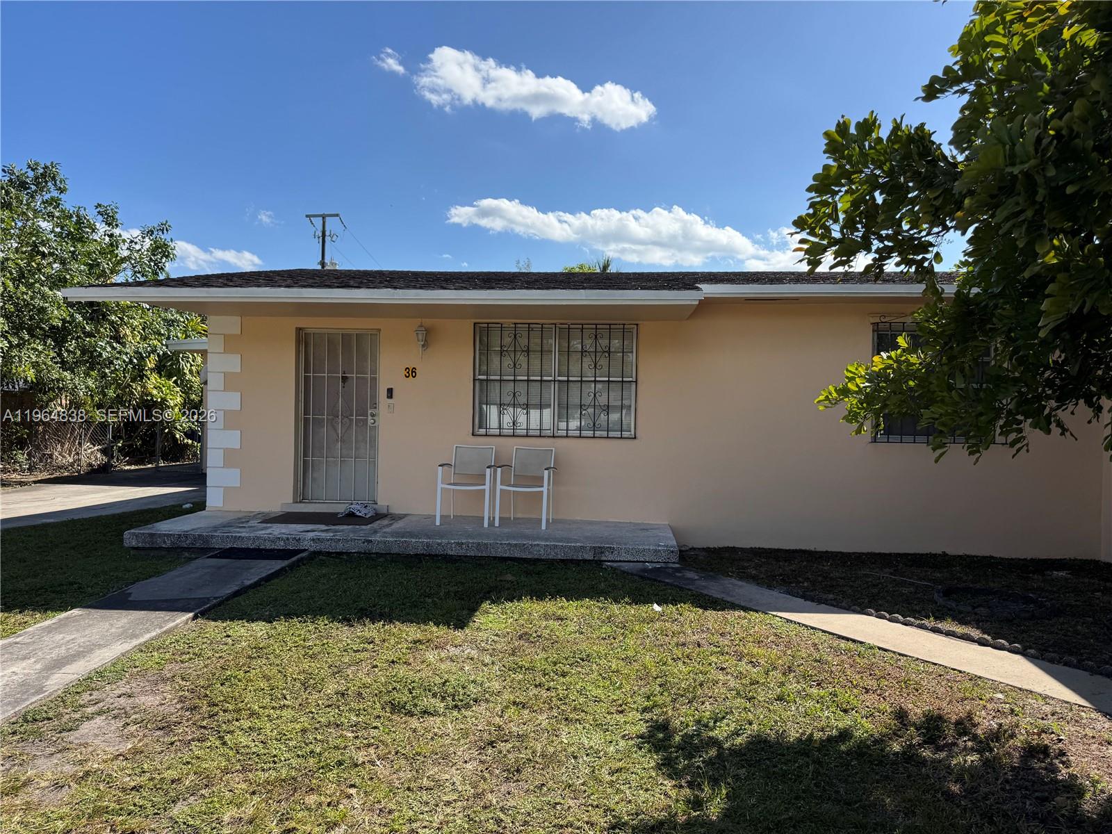 A single-story peach-colored house features a front porch, security bars on windows, and a lawn — 36 NW 151st St, Miami FL 33169, MIAMI, FL