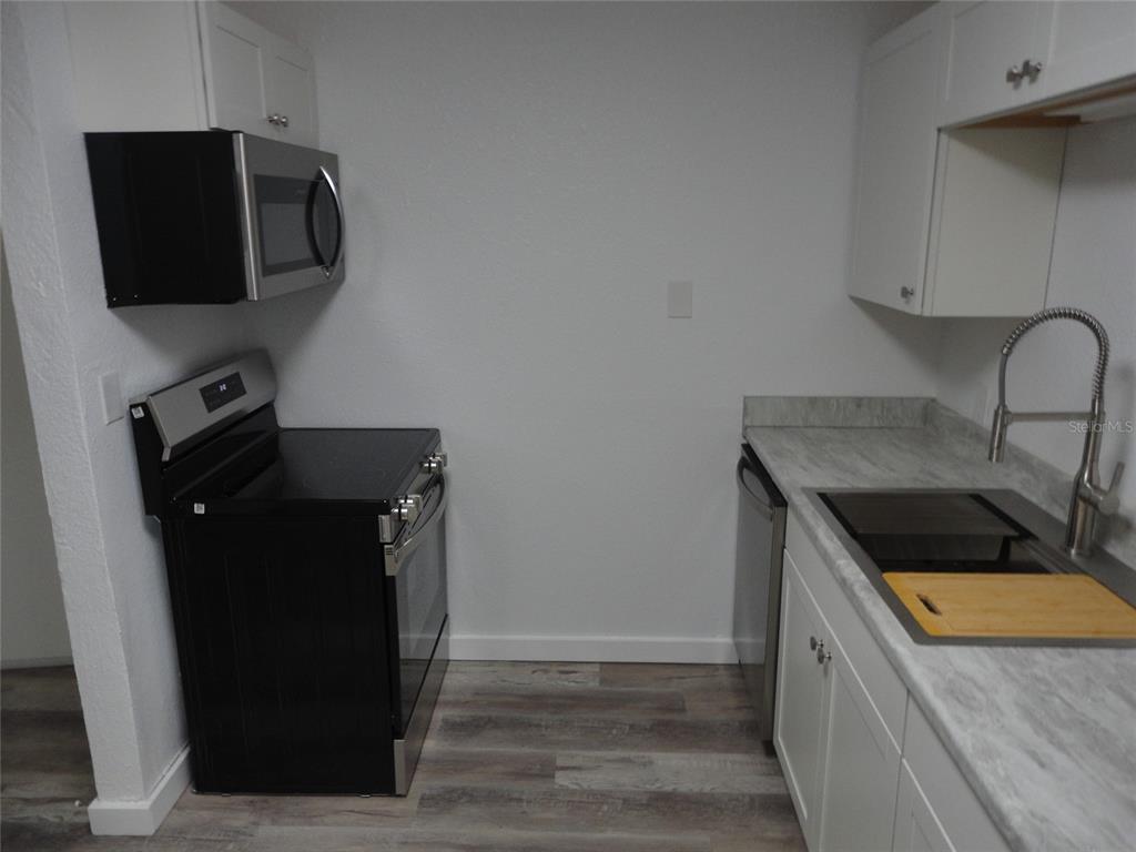 A kitchen features white cabinets, stainless steel appliances, and a gray countertop — 1015 SW 9TH STREET UNIT C-24, GAINESVILLE, FL