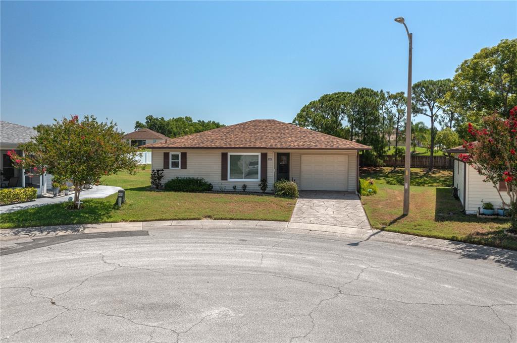 A single-story house with beige siding, a brown shingled roof, and a paved driveway — 3245 PRAIRIE DUNES CIRCLE E, LAKELAND, FL