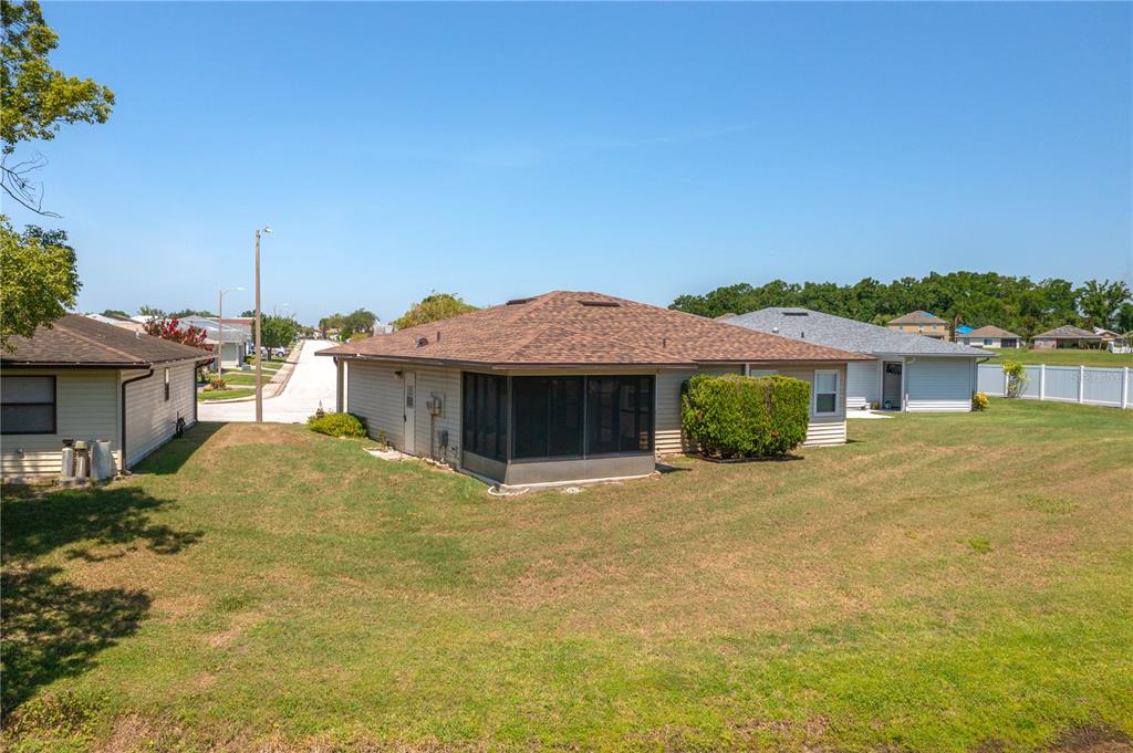 A rear exterior view of a single-story house with a screened-in porch and grassy yard — 3245 PRAIRIE DUNES CIRCLE E, LAKELAND, FL