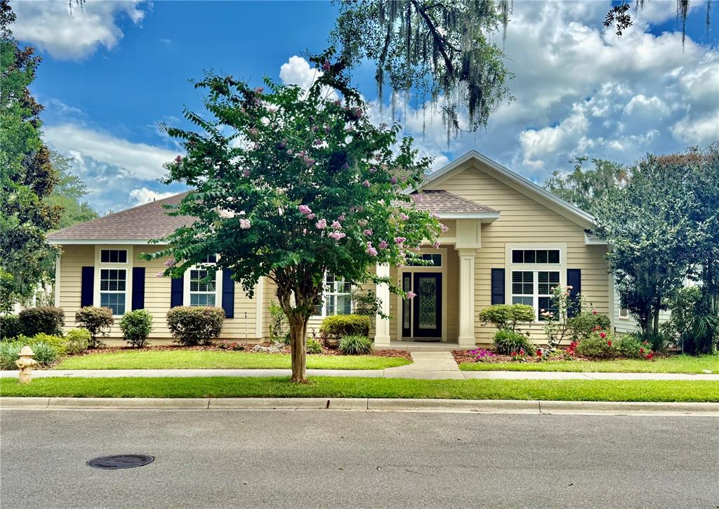 A beige house with a two-car garage and a blooming crape myrtle tree in front — 7384 SW 35TH LANE, GAINESVILLE, FL