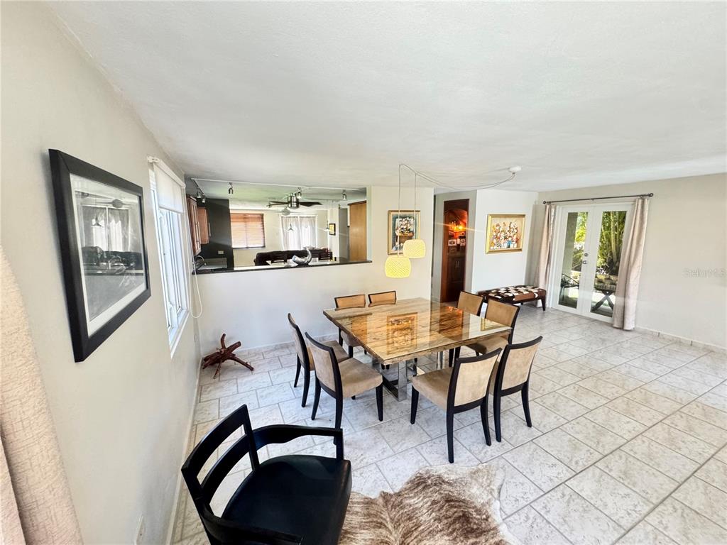 A dining room with a glass-topped table, tile flooring, and a pass-through to the kitchen — C4 AURORA UNIT C-4, HUMACAO, PR