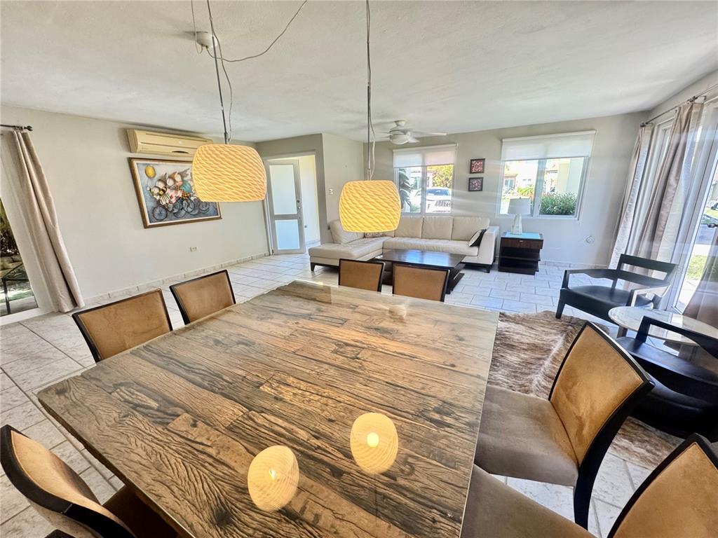 A dining area with a wooden table and pendant lights opens into a living room — C4 AURORA UNIT C-4, HUMACAO, PR