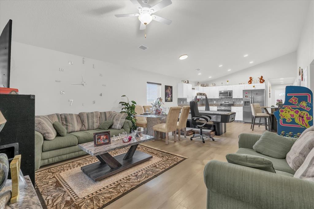 An open-concept living and dining area features green sofas, a pool table, and white cabinetry — 119 D STREET, LAKE WALES, FL