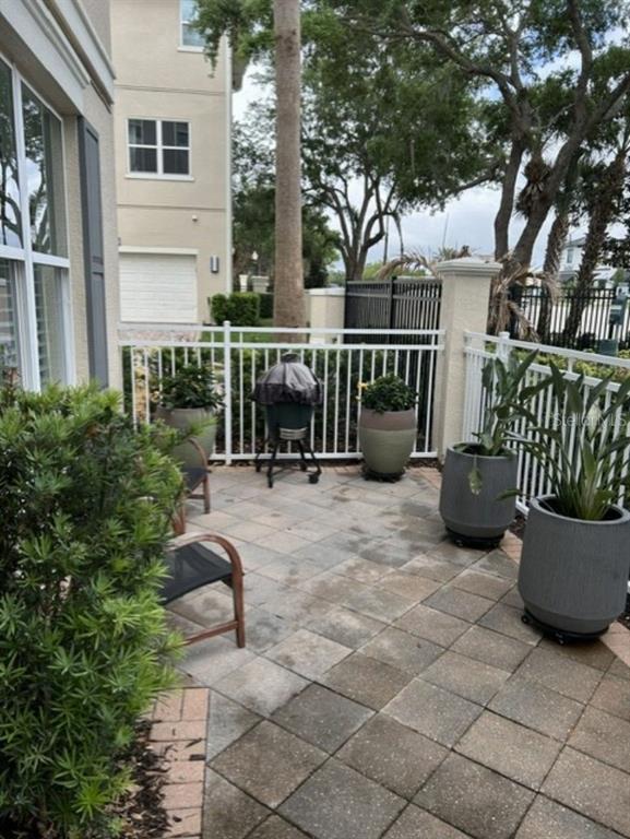 A paved patio features potted plants, a covered grill, and a white metal fence — 641 HANGNEST LANE, LAKE MARY, FL