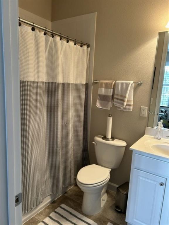 A bathroom features a shower with a patterned curtain, a toilet, and a white vanity — 641 HANGNEST LANE, LAKE MARY, FL