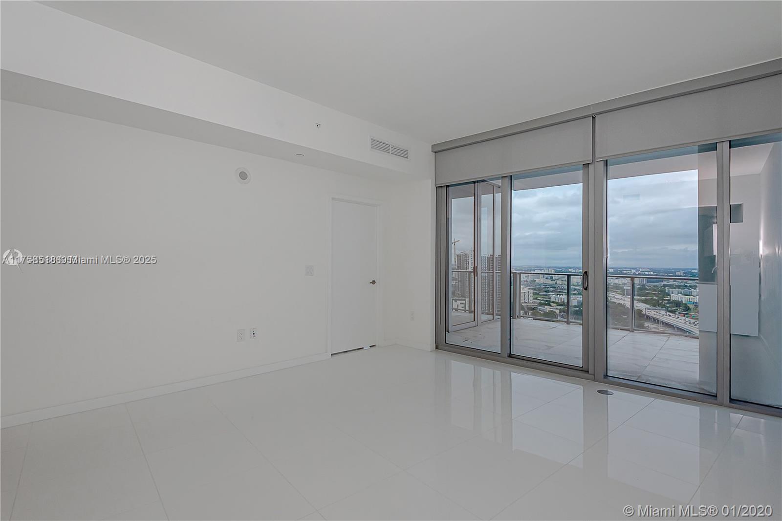 A minimalist room with white tile floors, white walls, and a glass balcony door — 851 NE 1st Ave # 2600, Miami FL 33132, MIAMI, FL