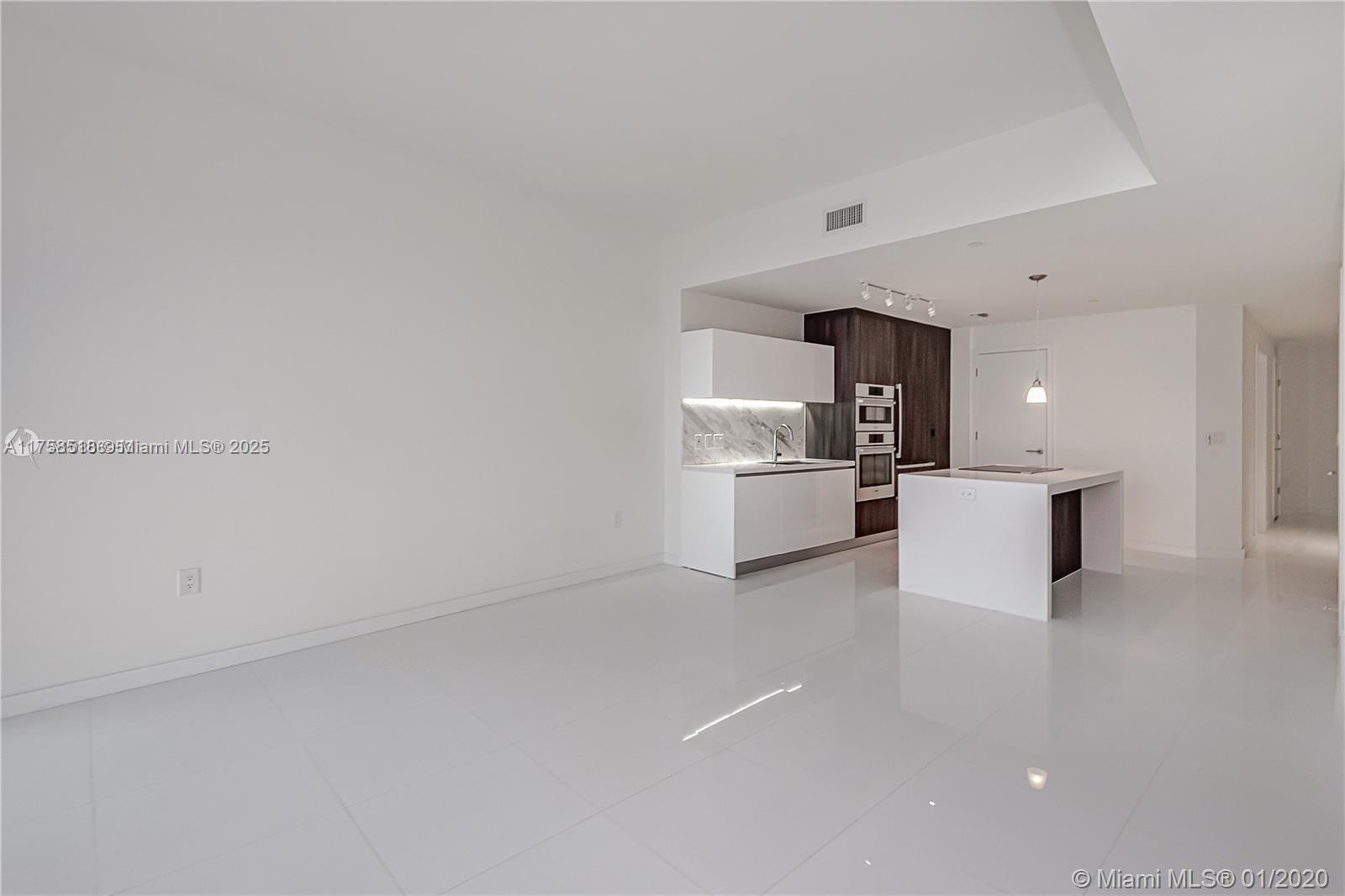 A modern kitchen features white cabinetry, a marble backsplash, and a central island — 851 NE 1st Ave # 2600, Miami FL 33132, MIAMI, FL