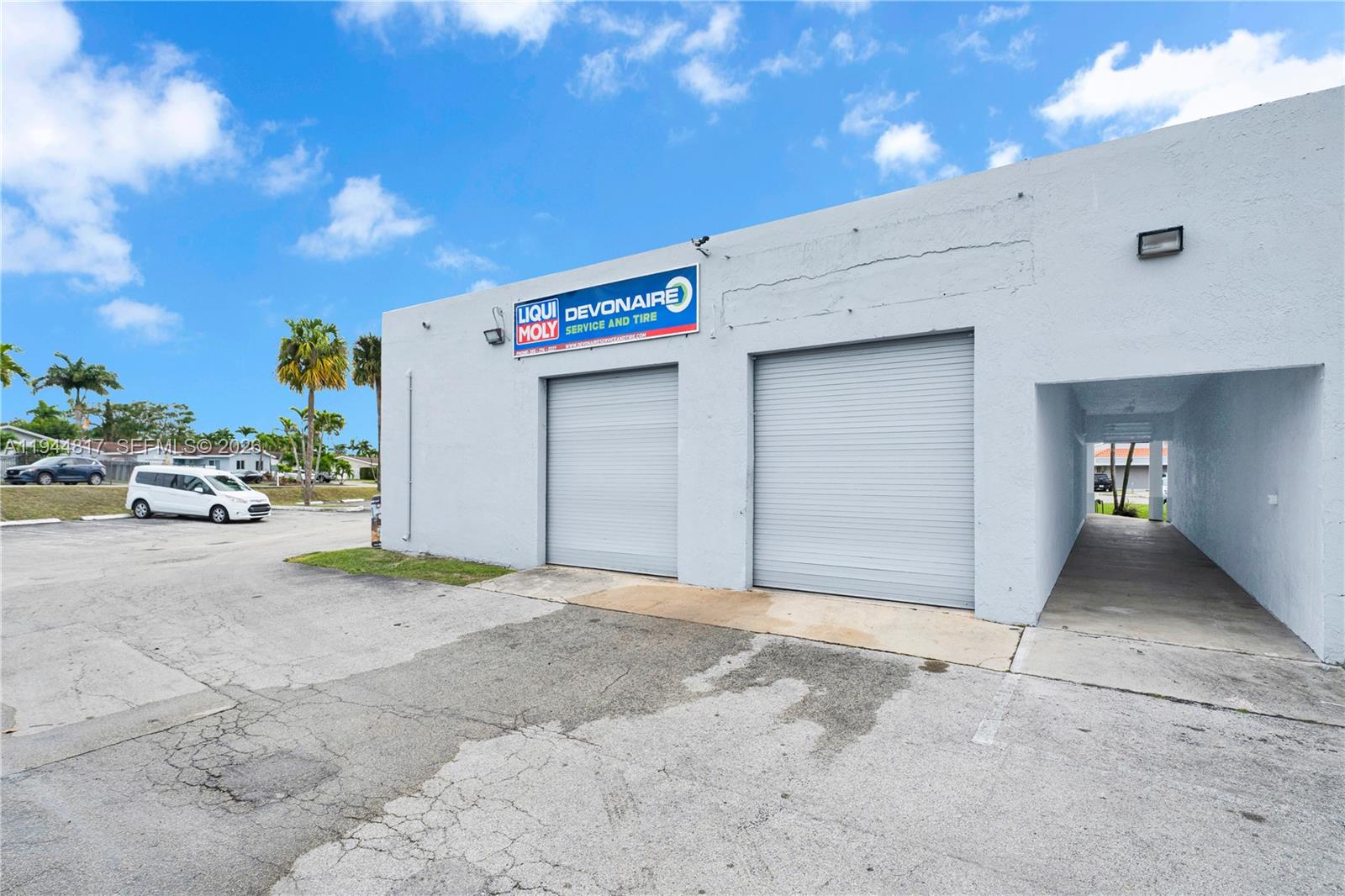The exterior of a commercial building features two roll-up garage doors and a covered walkway — 12225 SW 112th St, Miami FL 33186, MIAMI, FL