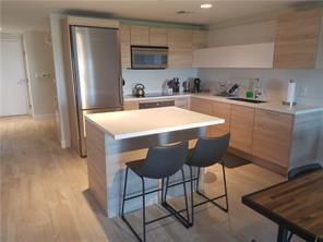 A modern kitchen features light wood cabinetry, a stainless steel refrigerator, and a central island — 16385 Biscayne Boulevard # 1018, North Miami Beach FL 33160, NORTH MIAMI BEACH, FL