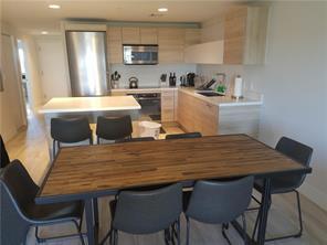A kitchen with light wood cabinets and a dining area with a wooden table — 16385 Biscayne Boulevard # 1018, North Miami Beach FL 33160, NORTH MIAMI BEACH, FL