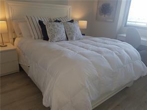 A bedroom features a white bed with a down comforter, two nightstands, and a desk — 16385 Biscayne Boulevard # 1018, North Miami Beach FL 33160, NORTH MIAMI BEACH, FL
