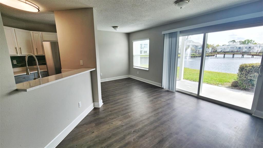 An open-concept living area features wood-look flooring, a kitchen breakfast bar, and sliding glass doors — 2528 WOODGATE BOULEVARD UNIT 102, ORLANDO, FL