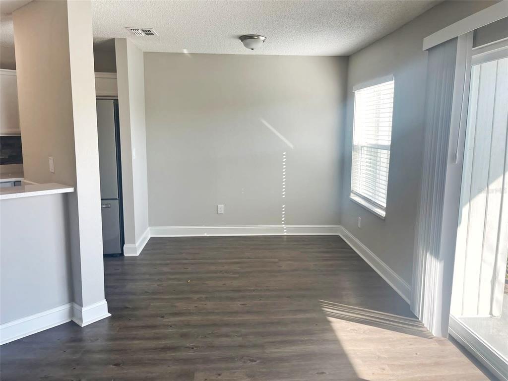 An empty dining area features grey walls, wood-look flooring, a ceiling light, and sliding doors — 2528 WOODGATE BOULEVARD UNIT 102, ORLANDO, FL