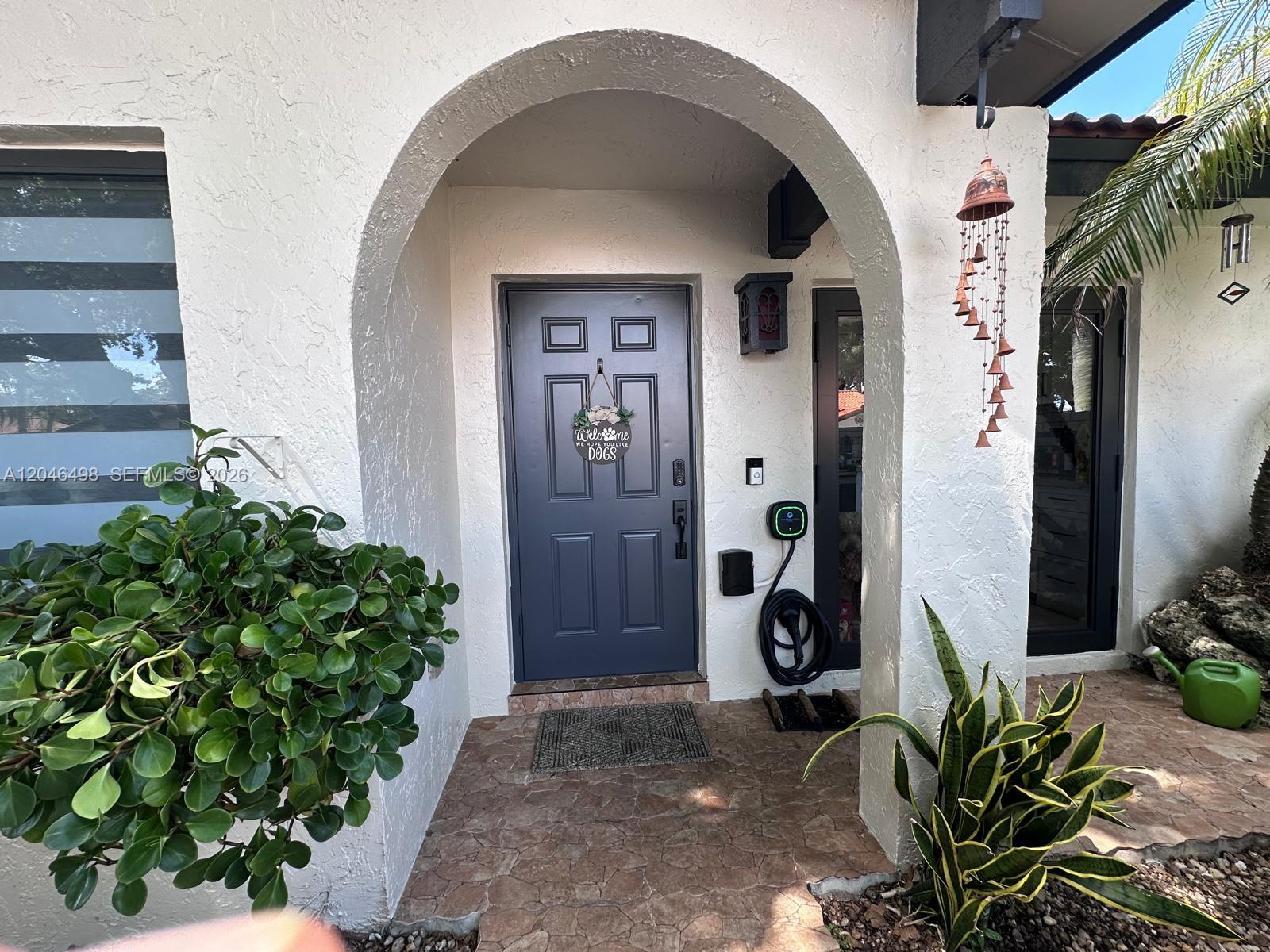 A front entryway features a dark gray door, an arched opening, and a wall-mounted charger — 6633 NW 178th Ter, Hialeah FL 33015, HIALEAH, FL