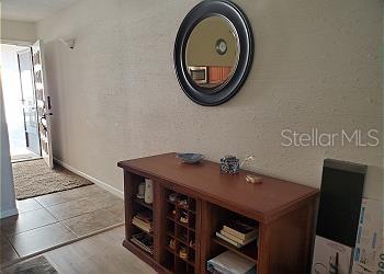 A wooden console table sits against a wall beneath a round mirror in an entryway — 6219 PALMA DEL MAR BOULEVARD S UNIT 206, ST PETERSBURG, FL