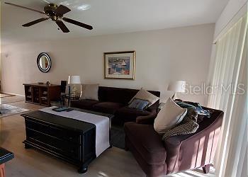 A living room features a dark brown sofa, an armchair, and a black coffee table — 6219 PALMA DEL MAR BOULEVARD S UNIT 206, ST PETERSBURG, FL