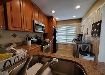 A kitchen features wood cabinets, stainless steel appliances, a double sink, and a breakfast nook — 6219 PALMA DEL MAR BOULEVARD S UNIT 206, ST PETERSBURG, FL
