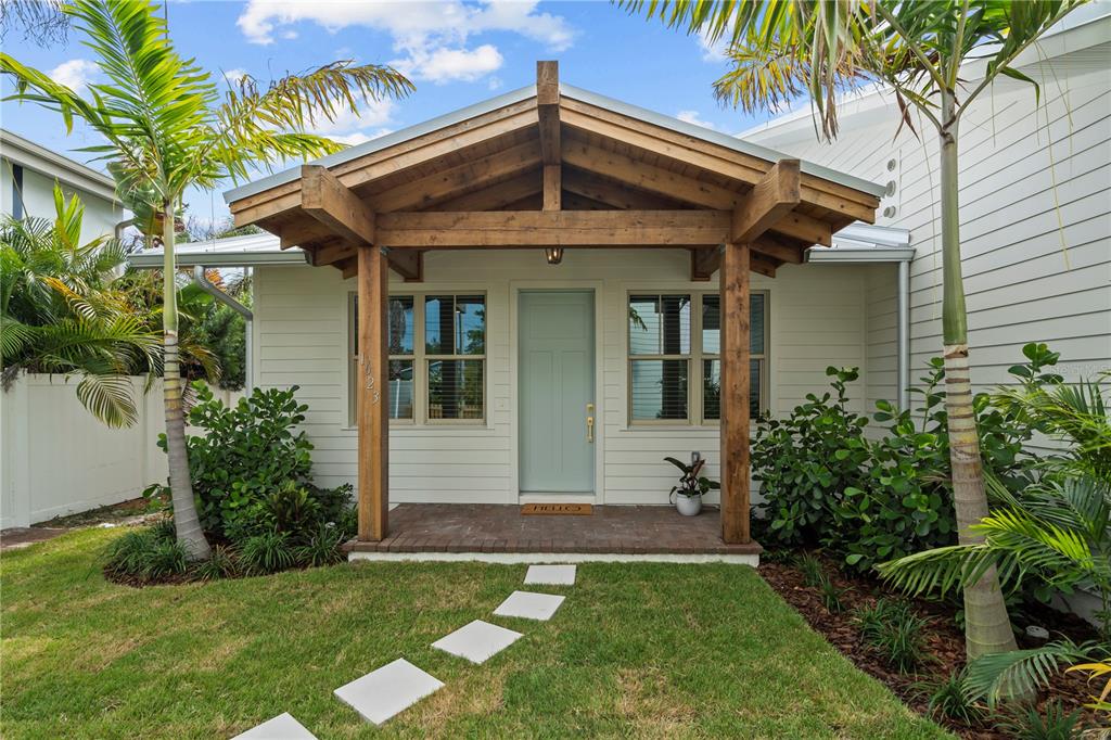 A front view of a house with a wooden porch, light blue door, and palm trees — 1623 31ST AVENUE N, ST PETERSBURG, FL