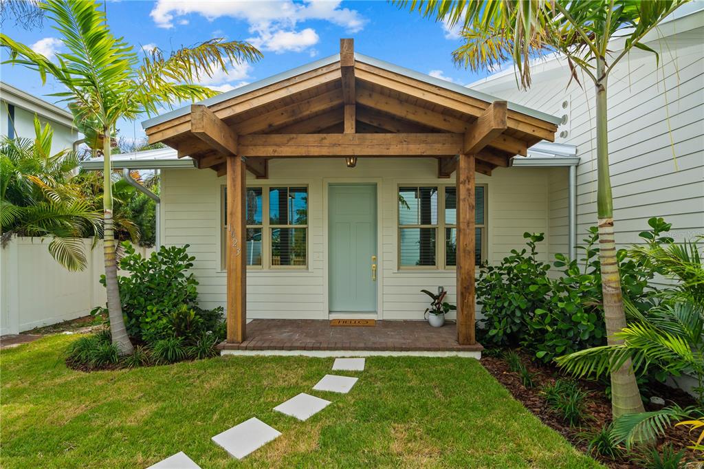 A light-colored house exterior features a wooden porch, a light blue door, and palm trees — 1623 31ST AVENUE N, ST PETERSBURG, FL