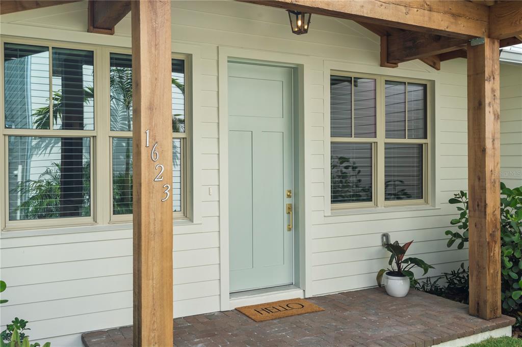 A light green front door with house numbers sits on a brick porch with wooden posts — 1623 31ST AVENUE N, ST PETERSBURG, FL