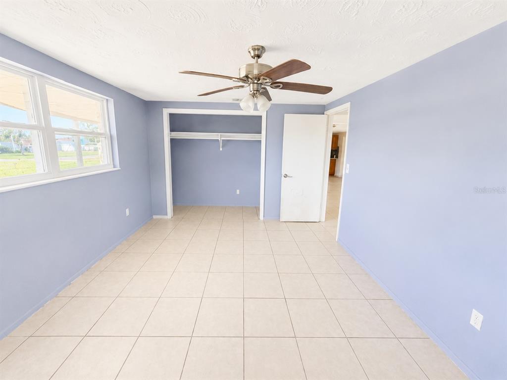 A room with light blue walls, tile flooring, a ceiling fan, and an open closet — 3303 EISENHOWER DRIVE, HOLIDAY, FL
