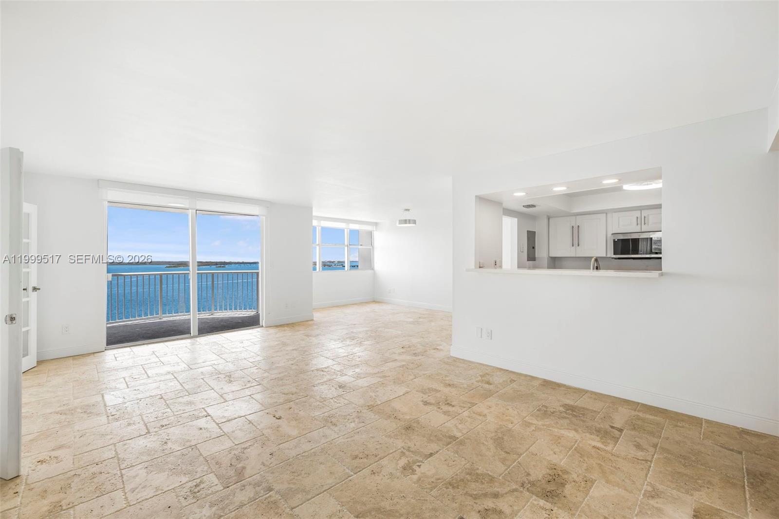An open-concept living area features light-colored tile flooring, white walls, and a view of water — 1420 Brickell Bay Dr # 1401A, Miami FL 33131, MIAMI, FL