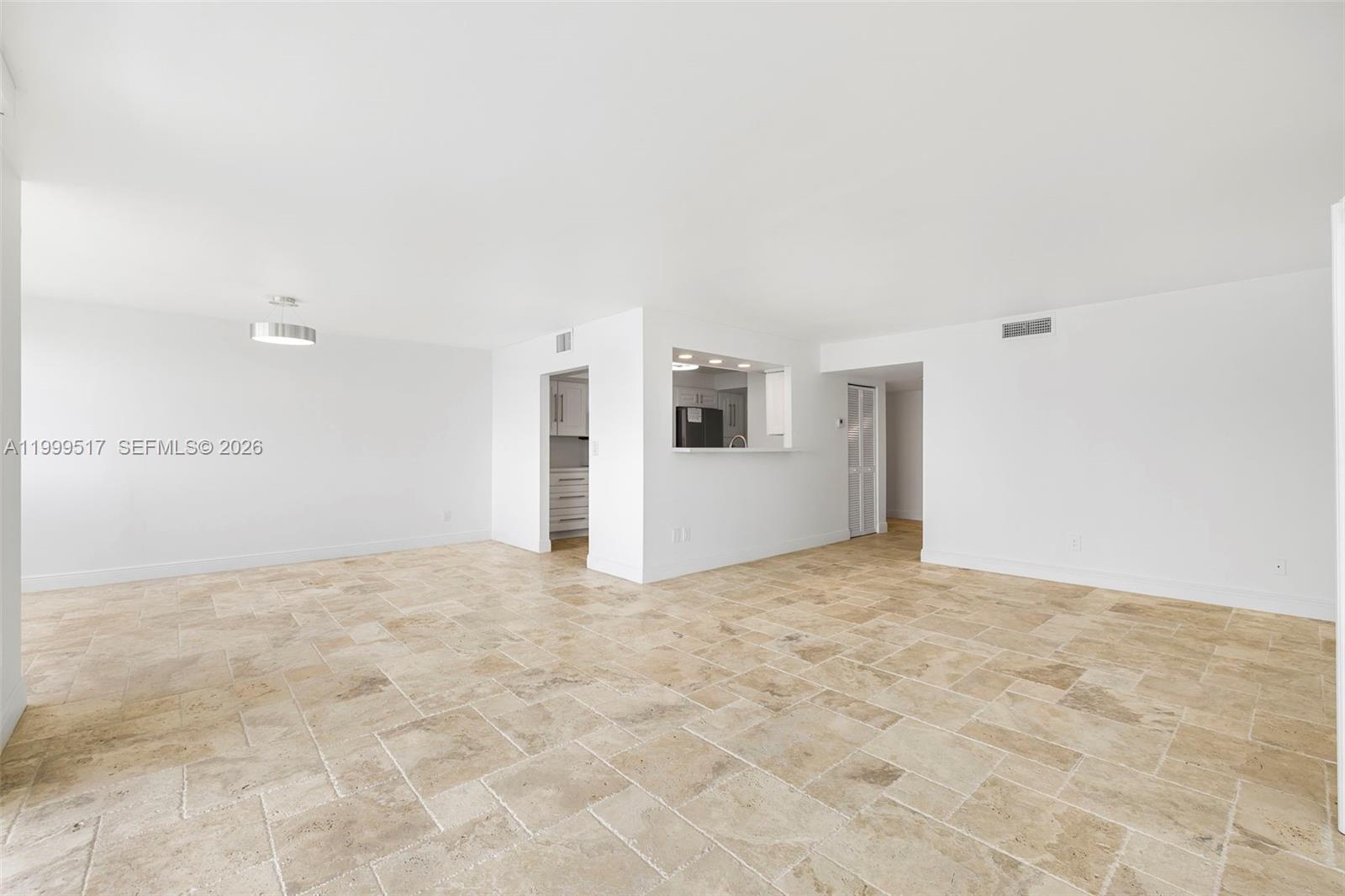 An open-concept living area features light-colored tile flooring and a pass-through kitchen window — 1420 Brickell Bay Dr # 1401A, Miami FL 33131, MIAMI, FL