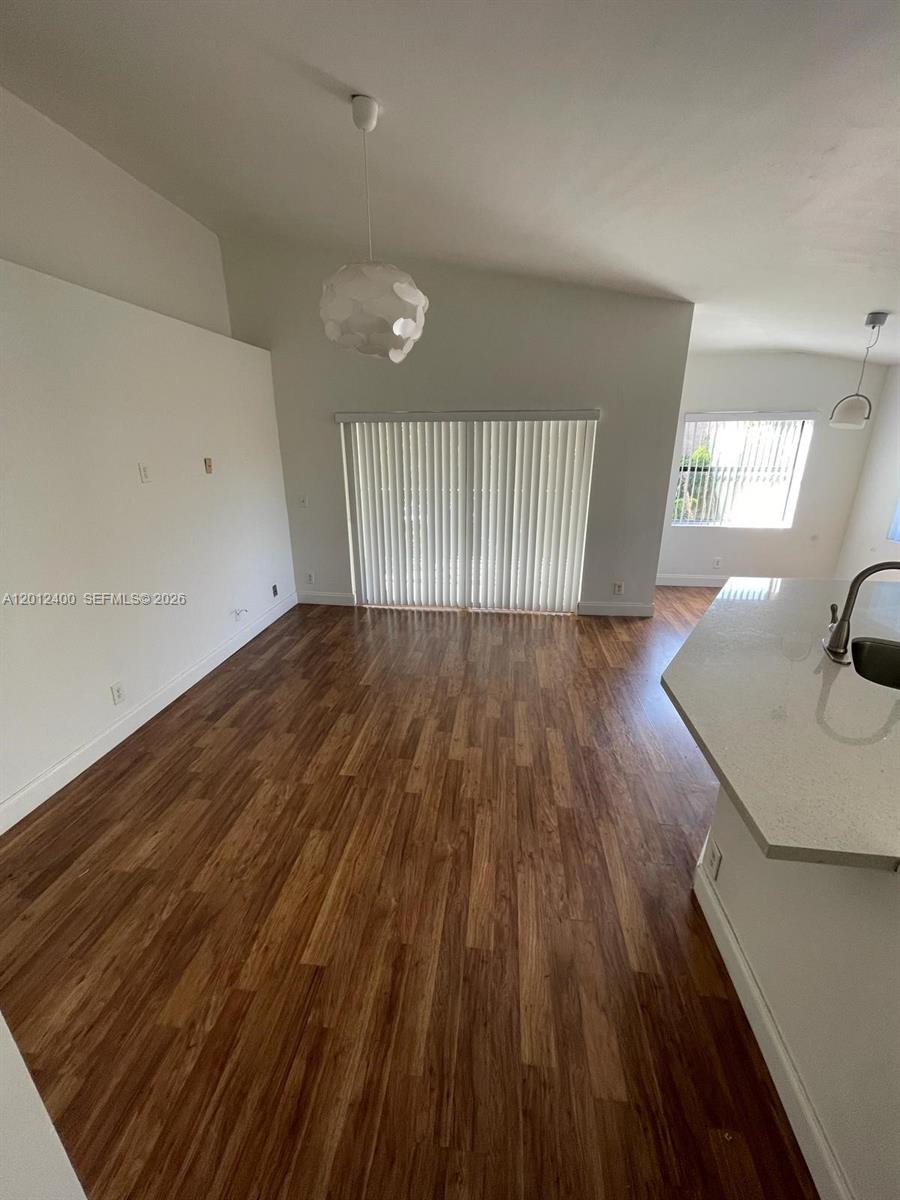 This room features wood-look flooring, a white pendant light, and a sliding glass door — 9999 Summerbreeze Dr # 212, Sunrise FL 33322, SUNRISE, FL