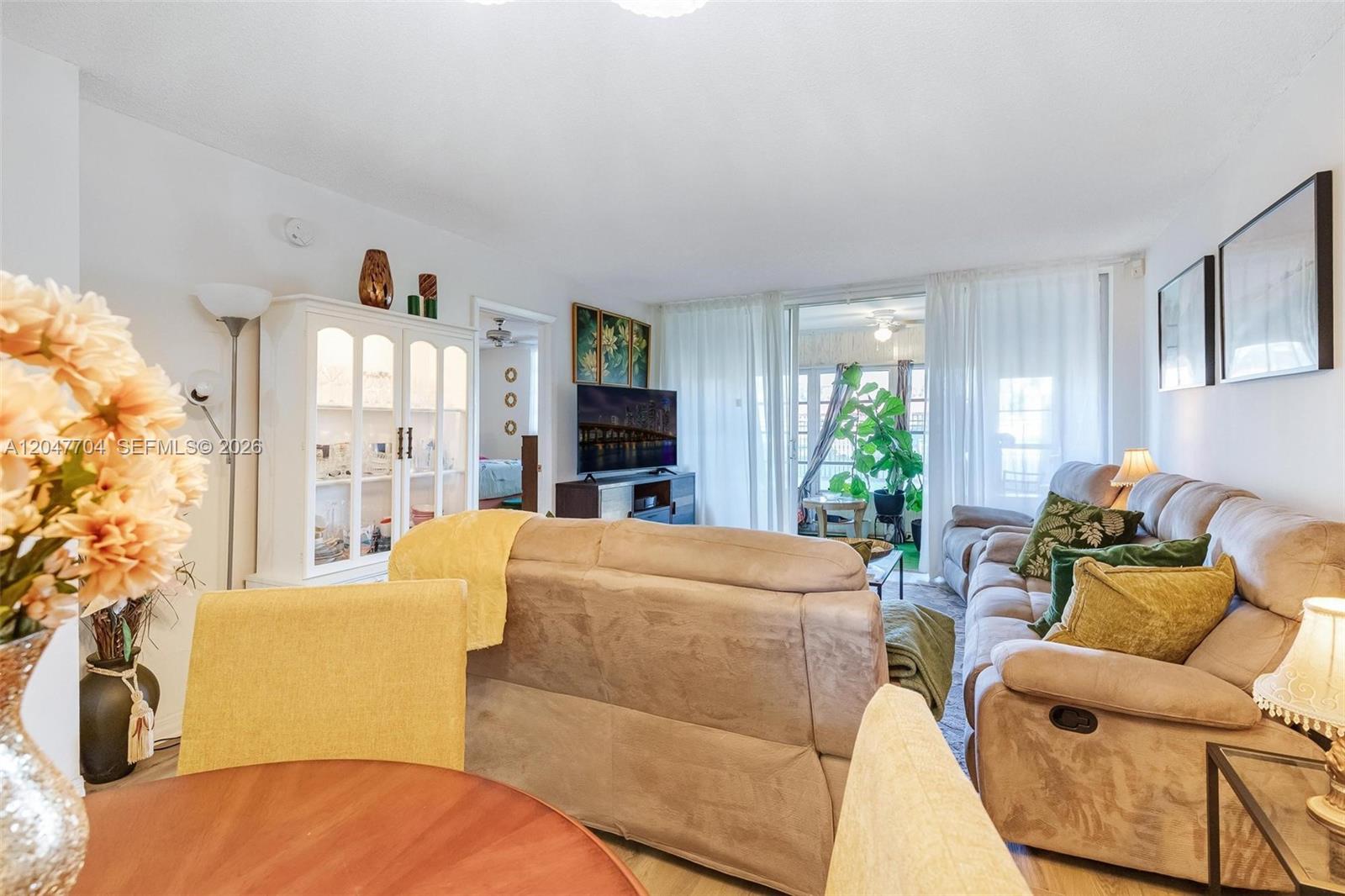 A living room features a beige sofa, a dining area, and a glass-enclosed balcony — 6000 NW 64th Ave # 110, Tamarac FL 33319, TAMARAC, FL