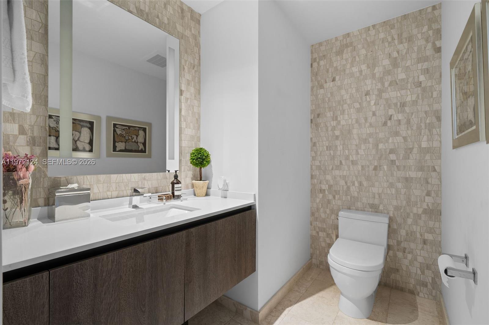 A modern bathroom features a floating wood vanity, white countertop, and textured stone accent walls — 68 SE 6th St # 3209, Miami FL 33131, MIAMI, FL