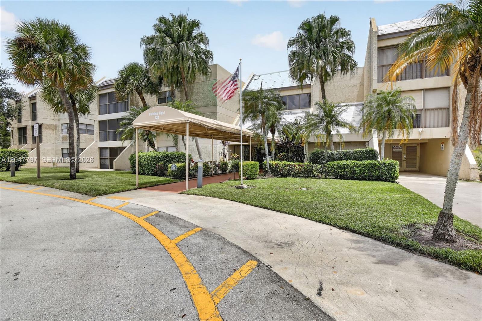 A multi-story apartment building features a tan facade, a covered entrance, and surrounding palm trees — 220 Lakeview Dr # 210, Weston FL 33326, WESTON, FL