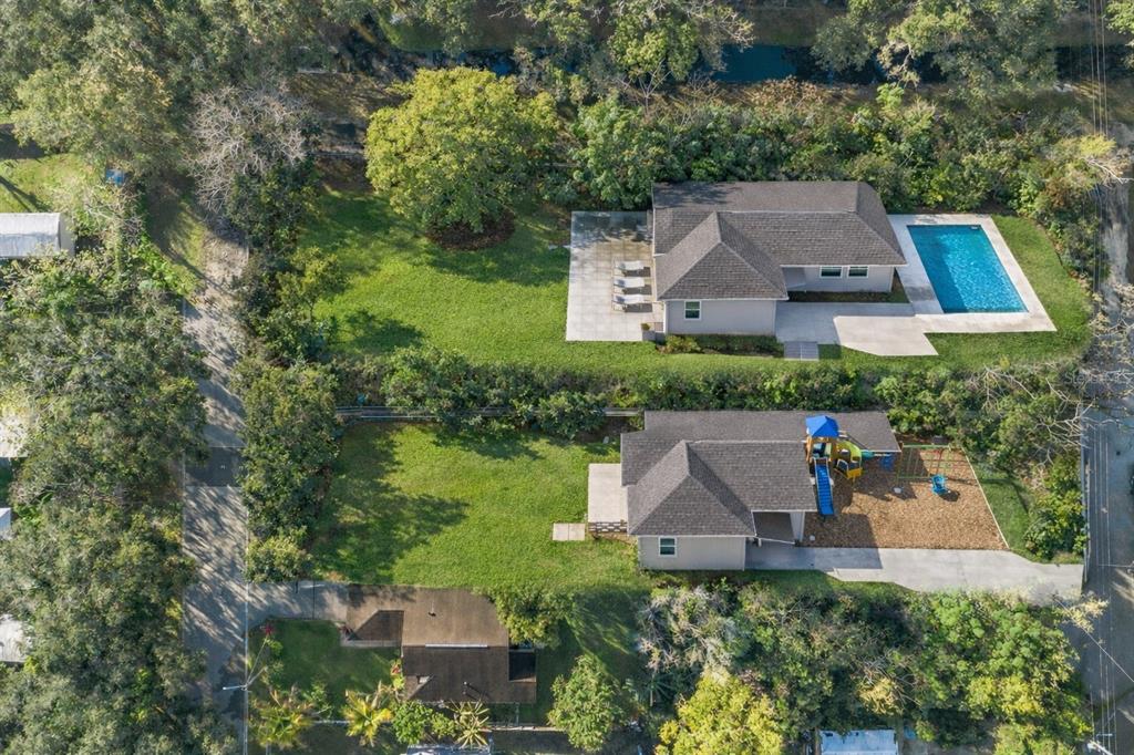 An aerial view shows two adjacent houses with large backyards, a swimming pool, and playground — 3RD AVENUE, ORLANDO, FL