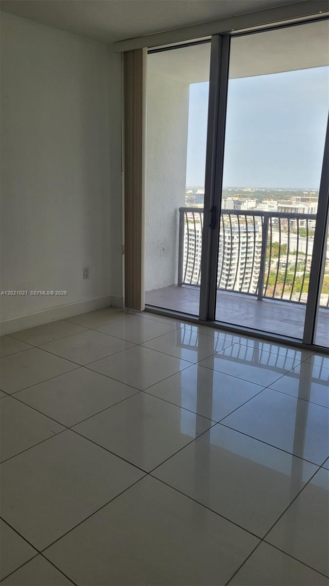 A room with light-colored tile flooring features a sliding glass door leading to a balcony — 1750 N Bayshore Dr # 3311, Miami FL 33132, MIAMI, FL