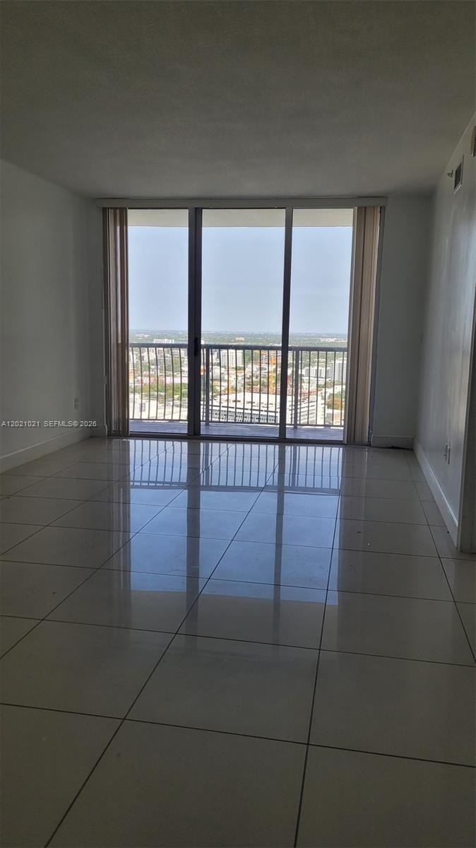 An empty room with white walls, light tile flooring, and a balcony with city views — 1750 N Bayshore Dr # 3311, Miami FL 33132, MIAMI, FL