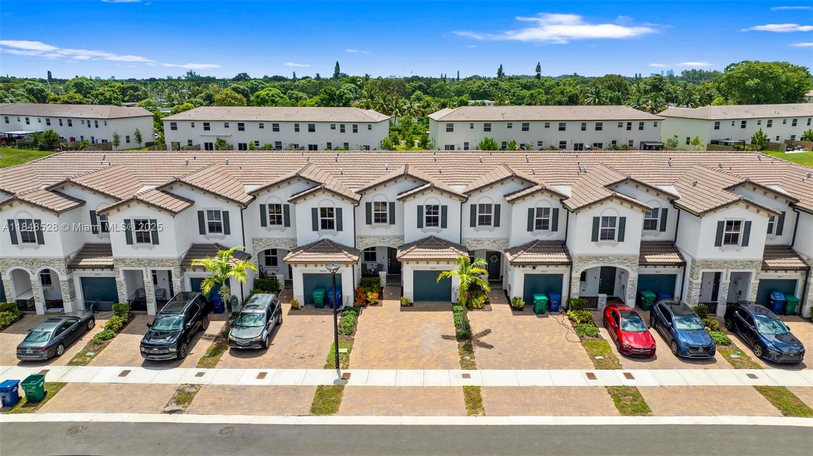 An aerial view of a row of two-story townhouses with paved driveways and parked cars — 12625 NW 23rd Pl, Miami FL 33167, MIAMI, FL