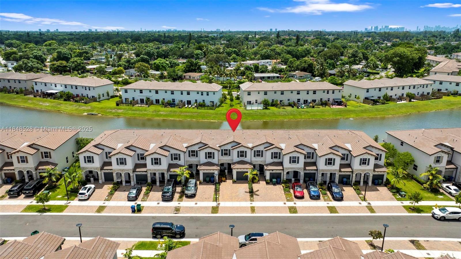 An aerial view shows a row of townhouses with a canal and residential neighborhood behind — 12625 NW 23rd Pl, Miami FL 33167, MIAMI, FL