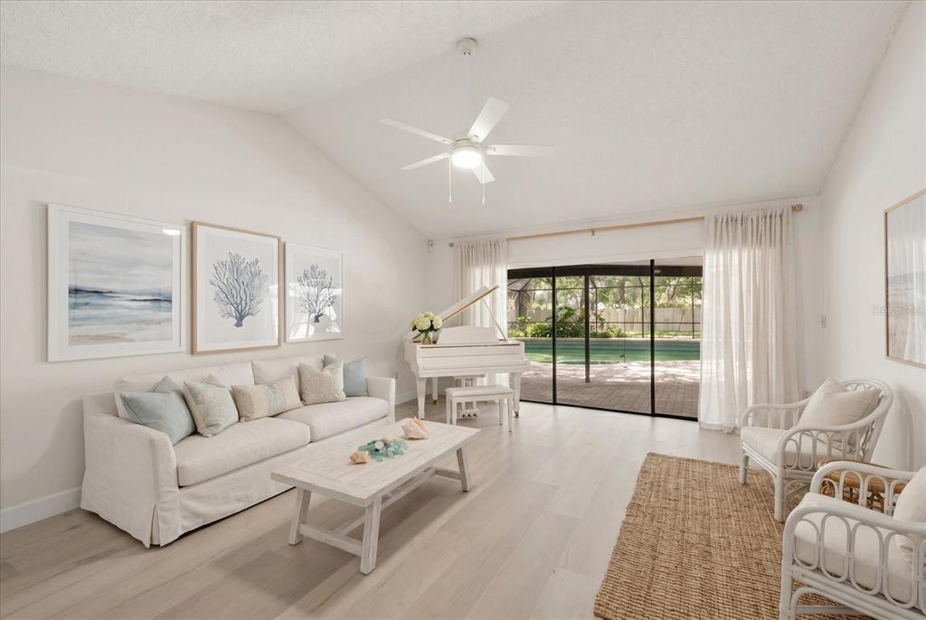 A bright living room features a white piano, light wood floors, and a sliding glass door — 3408 CULLENDALE DRIVE, TAMPA, FL