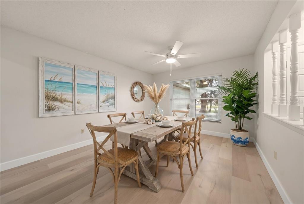 A dining room features a wooden table, cross-back chairs, coastal artwork, and light wood flooring — 3408 CULLENDALE DRIVE, TAMPA, FL