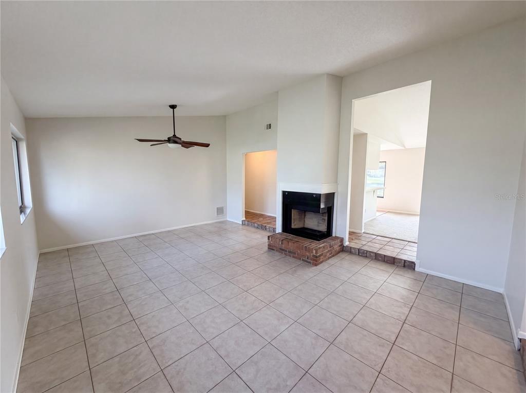 A living room with light tile flooring, a ceiling fan, and a brick fireplace — 2631 ALABASTER AVENUE, ORLANDO, FL