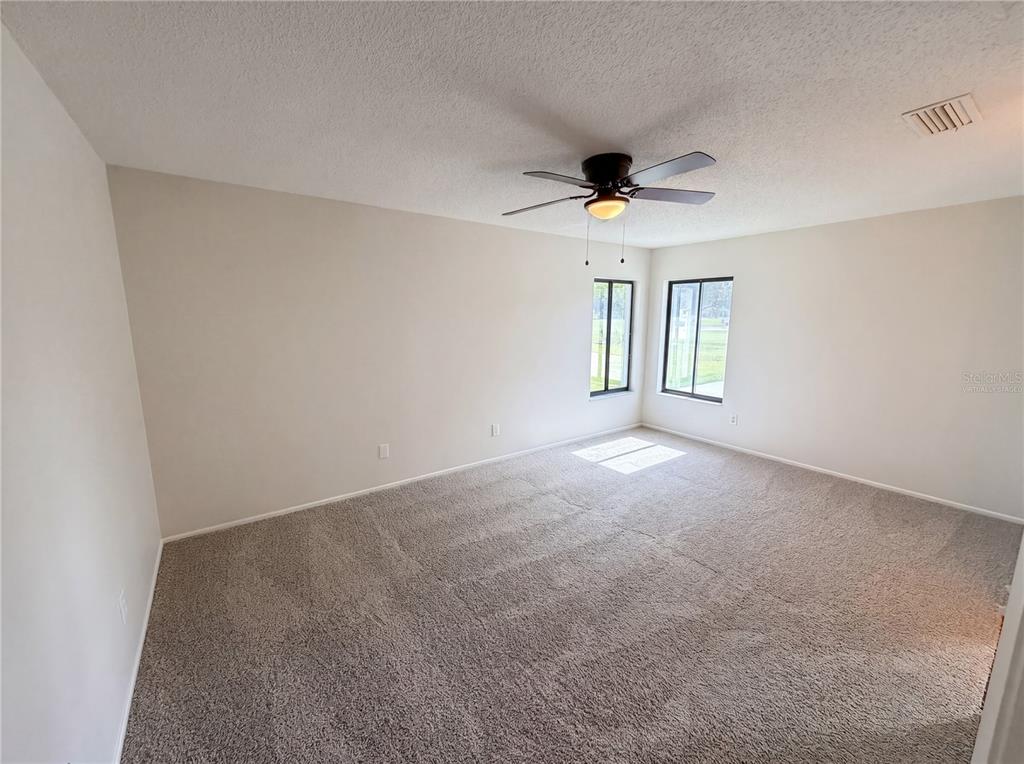 An empty bedroom features beige carpet, light-colored walls, a ceiling fan, and two windows — 2631 ALABASTER AVENUE, ORLANDO, FL