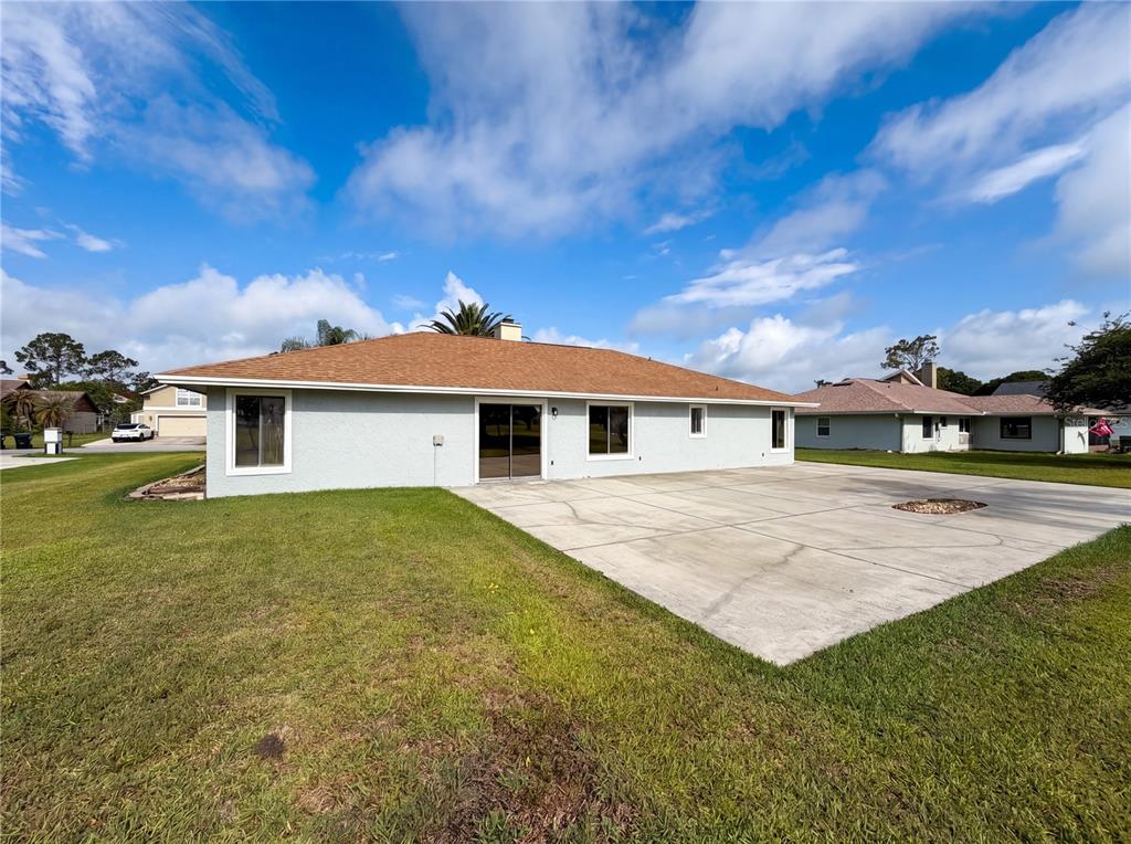 The rear exterior of a single-story house features a concrete patio and a grassy yard — 2631 ALABASTER AVENUE, ORLANDO, FL
