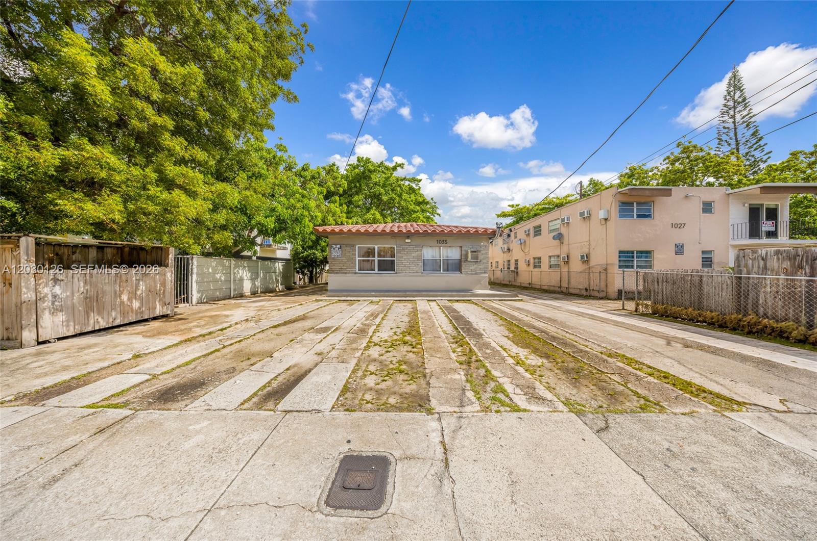 A single-story building with a tiled roof sits behind a large concrete parking area — 1035 NW 4th St, Miami FL 33128, MIAMI, FL