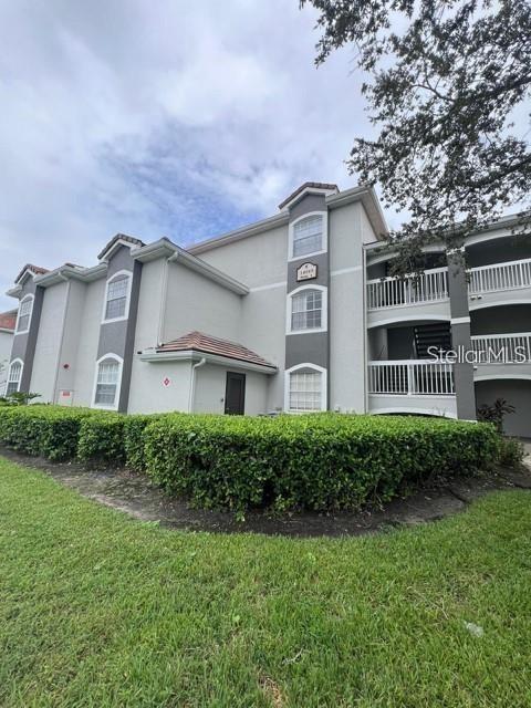 A three-story apartment building with light gray stucco walls and white railings — 14049 FAIRWAY ISLAND DRIVE UNIT 127, ORLANDO, FL