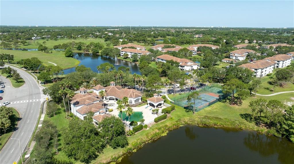 An aerial view shows a clubhouse with a pool, tennis courts, and surrounding residential buildings — 14049 FAIRWAY ISLAND DRIVE UNIT 127, ORLANDO, FL